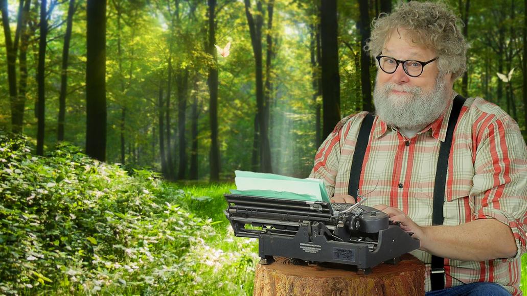 Knute standing in the forest at a typewriter