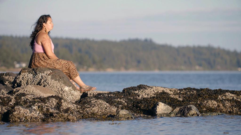 woman sitting on rocks looking out to the ocean
